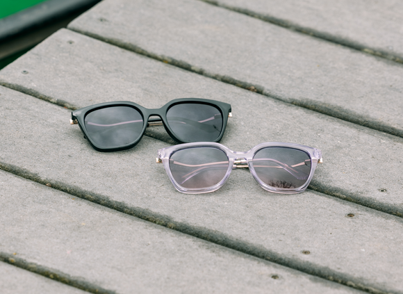 Two pairs of sunglasses on a wooden surface