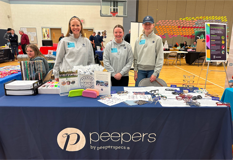 Peepers team members sorting donated eyewear and school supplies at a gymnasium adoption event