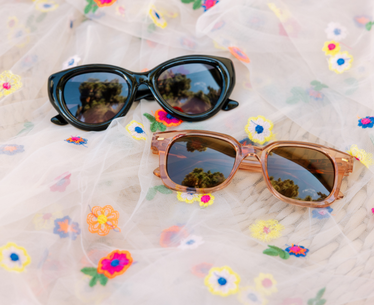 Two pairs of sunglasses on a floral fabric background