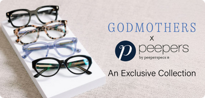Four pairs of eyeglasses on a white stand with 'Godmothers x Peepers' branding.