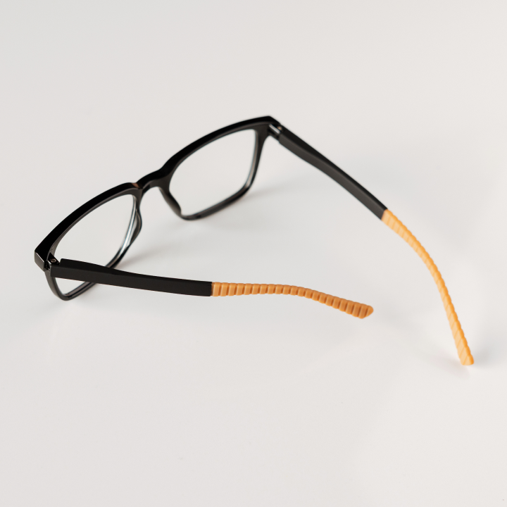 Black-framed glasses with orange arms on a light gray background