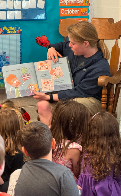 Young student reading a book during a Peepers classroom visit