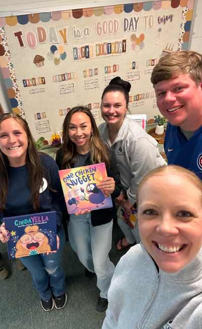 Peepers team members holding children's books at a school reading event