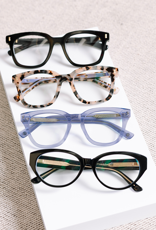 Four pairs of eyeglasses with different frames on a light surface