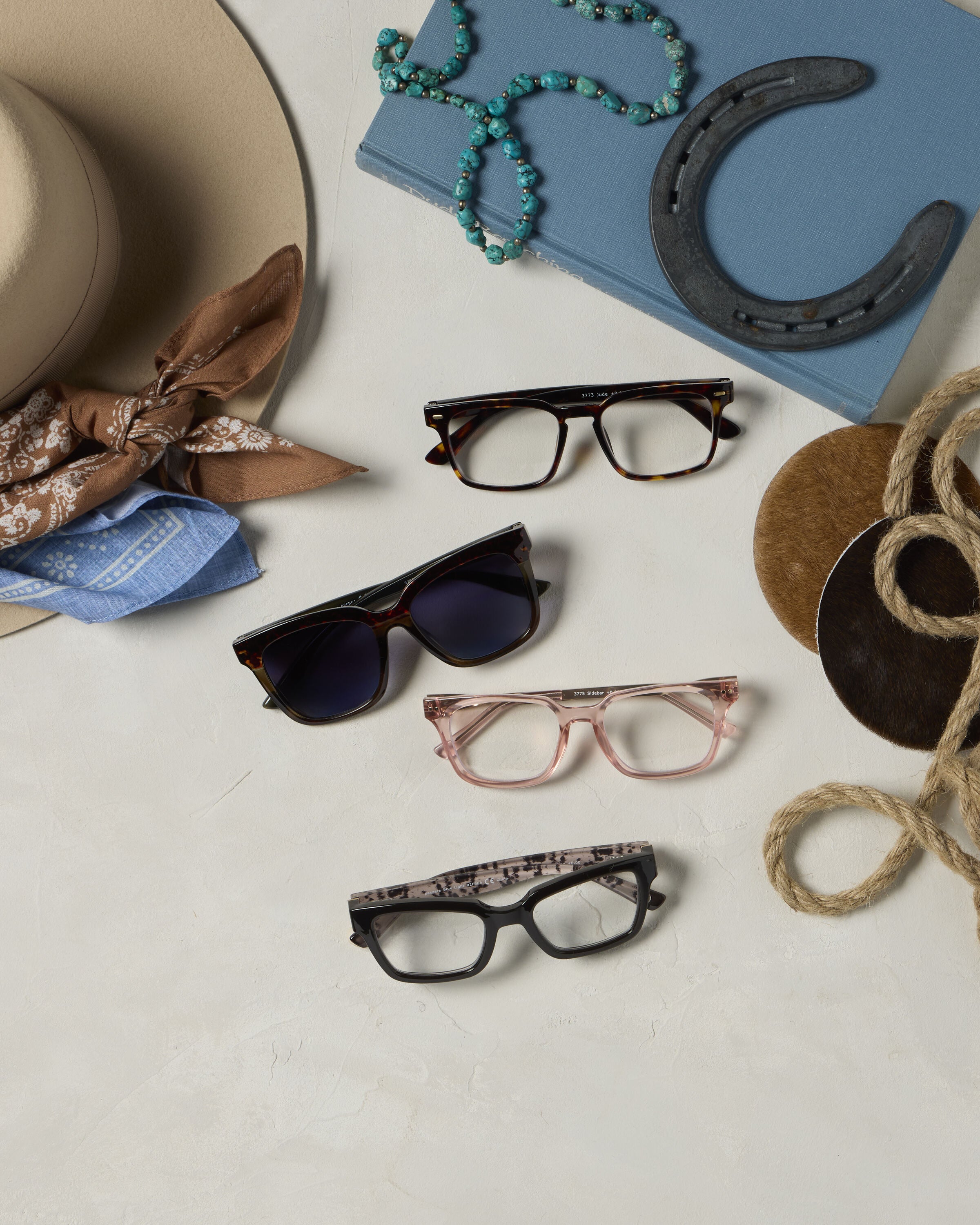 Four western-inspired eyewear styles arranged with cowboy hat, turquoise jewelry, and horseshoe